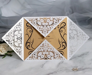 Laser cut lace invitation cover with golden inner card on white marble background