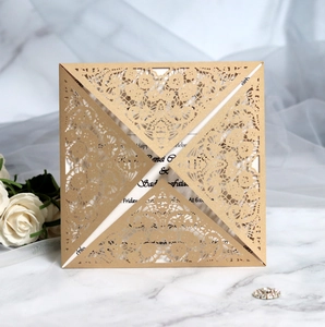 Detail of laser-cut champagne gold lace wedding invitation pocket on marble background