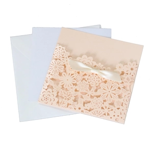 Elegant pink laser cut floral wedding invitation cards with satin bow and white envelopes
