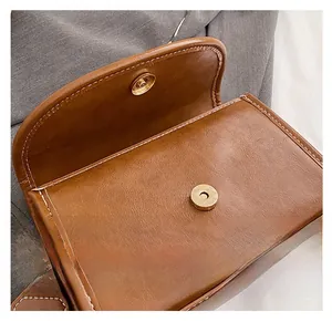 Detail of the magnetic snap closure on the brown PU leather handbag with white stitching