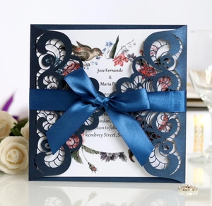 Detailed laser-cut pocket of navy blue wedding invitation with elegant ribbon bow