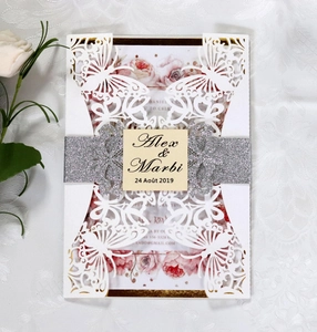 Macro shot of laser-cut butterfly invitation with silver glitter belt and card