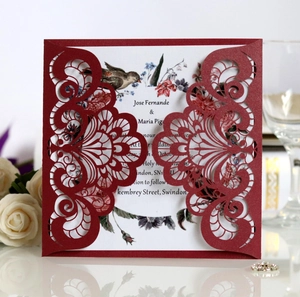 Detail of laser-cut wedding invitation with deep red lace patterns and vintage floral inner card