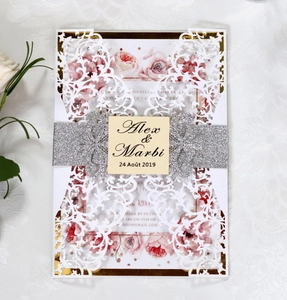 Detail of laser-cut lace wedding invitation with silver glitter belt and floral inner page