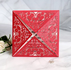 Close-up of red laser-cut lace invitation with elegant floral hollow patterns and white inner card
