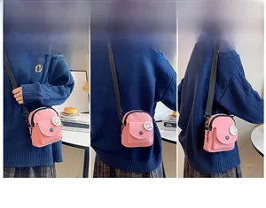 Détail d'un mini sac bandoulière en toile rose avec bandoulière et badge de dessin animé