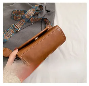 Detail view of brown PU leather bag base with contrast stitching and ethnic wide strap