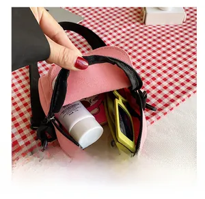 Vue détaillée de la capacité interne du sac bandoulière en toile rose avec accessoires