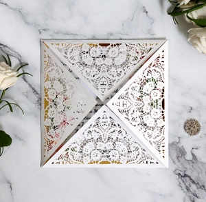Macro shot of white laser-cut lace invitation card with elegant gold inner sheet detail