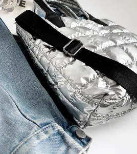 Detail of silver quilted bucket bag with adjustable black wide strap and metal buckle