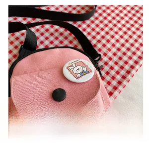 Détail du petit sac en toile rose avec un badge de lapin mignon et une bandoulière noire