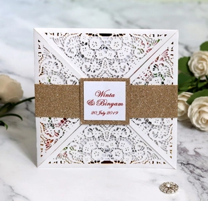 Detail of laser-cut wedding invitation with champagne gold glitter belly band and names