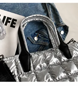 Detail of silver quilted bucket bag with metallic finish and black woven strap