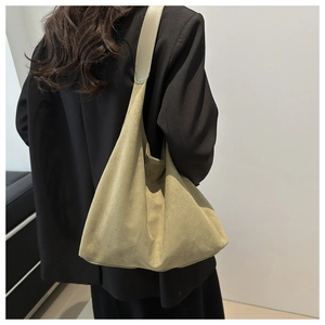 Detail view of moss green suede tote bag with wide strap on model's shoulder for work