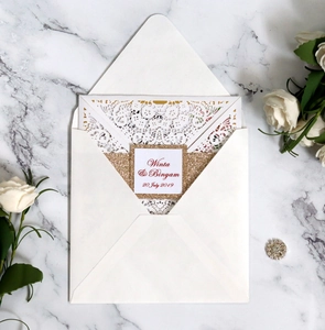 Detailed laser-cut wedding invitation with white lace pattern and gold glitter borders