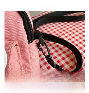 Détail du sac en toile rose montrant les crochets en plastique noir et la bandoulière