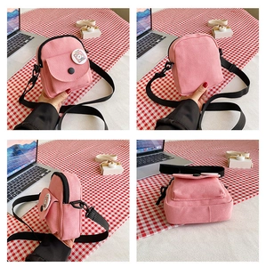 Vue détaillée du petit sac bandoulière en toile rose avec écusson lapin et sangle noire