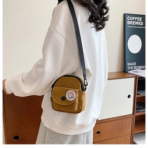 Détail du mini sac bandoulière en toile jaune moutarde avec un badge lapin mignon