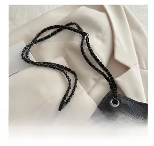 Détail du sac cabas à paillettes noires avec bandoulière chaîne sur un blazer blanc