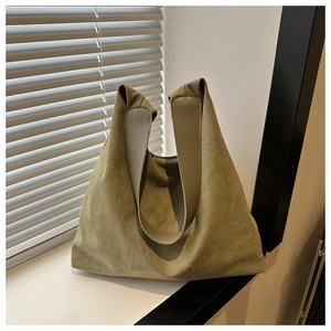 Close-up of olive green matte suede tote bag with leather handles by window shutters
