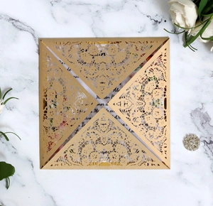 Macro shot of gold laser-cut lace invitation cover on elegant white marble surface