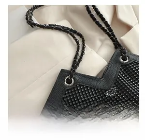 Détail de la bandoulière en chaîne et de la texture en strass de ce sac fourre-tout noir