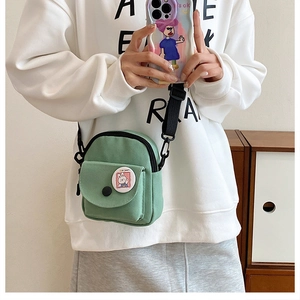 Détail du sac bandoulière en toile verte avec patch lapin Hi bear et sangle réglable