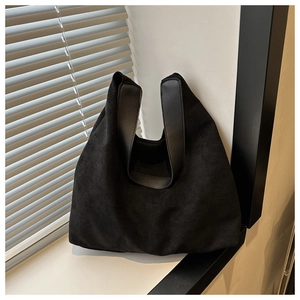 Detail of black matte tote bag with premium leather handles on a natural lit windowsill