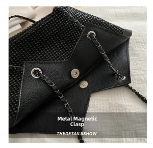 Détail du fermoir magnétique et de la chaîne sur le sac cabas en cuir grainé noir