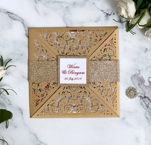 Detail of laser-cut gold wedding invitation with glitter belly band and custom card