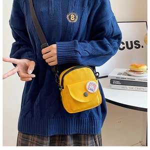Détail du petit sac bandoulière en toile jaune avec poche à rabat et broche lapin mignonne