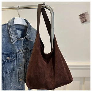 Detail of vintage brown suede tote bag texture hanging with a blue denim jacket