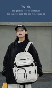 Close-up of white utility backpack featuring multiple pockets and fashion logo tag