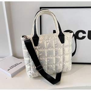 Détail d'un sac seau matelassé blanc avec poignées en cuir noir et bandoulière amovible