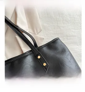 Detail of black lychee grain leather tote bag featuring gold metal rivets and edge finishing