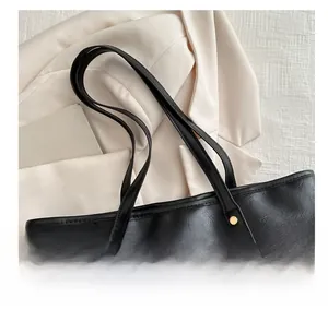 Detail of black faux leather tote with golden rivets and refined textured surface