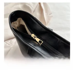 Detailed close-up of smooth golden metal zipper and black PU leather on a tote bag