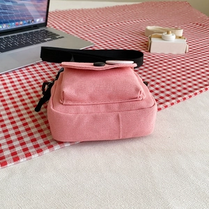Petit sac bandoulière en toile rose pour femme sur une nappe à carreaux rouges