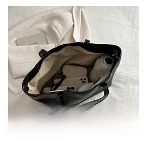 Top-down view of black faux leather tote bag interior showing large capacity and items