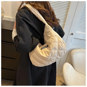 Détail d'un sac à bandoulière matelassé crème avec une texture douce et étiquette mode
