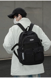 Rear view of a model wearing a large black retro streetwear backpack with multi-layer pockets