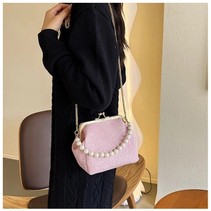 Detail of light pink glitter frame bag with pearl handle and golden chain on model