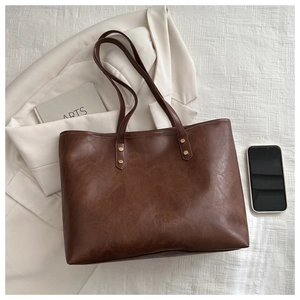 Macro shot of dark brown tote bag with vintage texture and gold rivet details