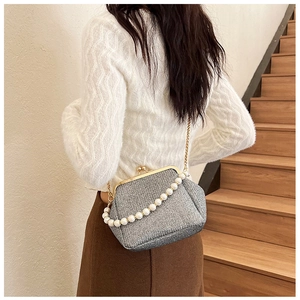 Detail of silver sequin crossbody bag with pearl handle and golden metal clasp