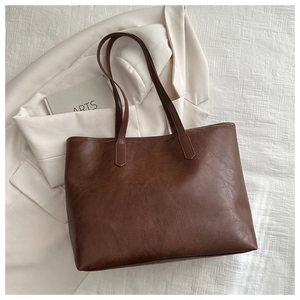 Detailed close-up of dark brown leather texture and stitching on large tote bag