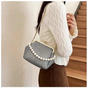 Detail of vintage gray woven handbag featuring elegant large pearl handle and metal clasp