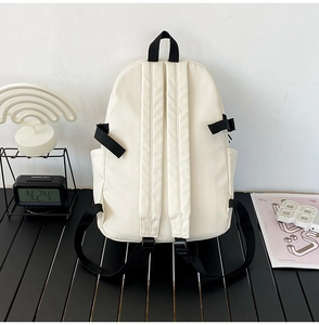 Rear view of white canvas backpack with black adjustable straps and side pockets