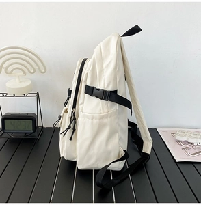 Side view detail of a minimalist white backpack featuring side buckles and black zipper closure