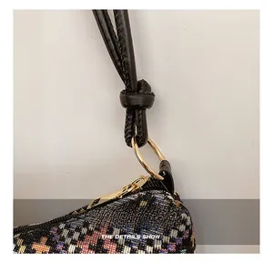 Dettaglio della ferramenta dorata e tracolla in pelle su borsa ricamata in tweed