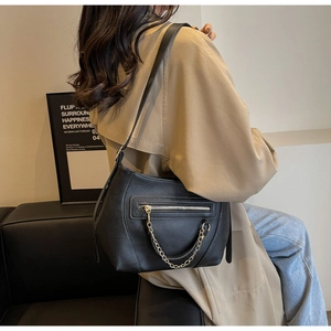 Close-up of black lychee grain leather tote featuring silver chain and zipper detail